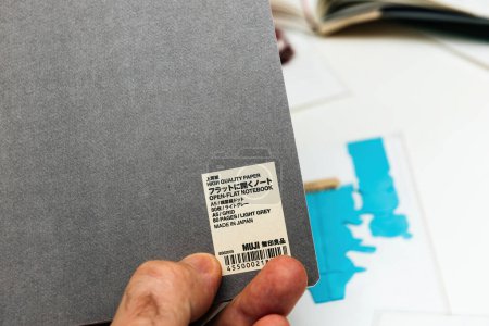 Photo for Bremen, Germany Dec 10, 2023: In a macro shot, a male hand delicately unboxes the latest Muji Light Ray Planner from Japan, revealing its high-quality paper and flat design, perfect for efficient - Royalty Free Image