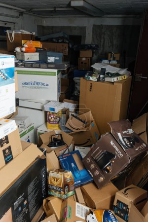Foto de Bremen, Alemania - 10 de diciembre de 2023: Un desordenado piso de garaje está lleno de múltiples paquetes de cartón de Amazon, Nespresso, Apple, Vitsoe y otras tiendas de comercio electrónico, lo que refleja los recientes - Imagen libre de derechos