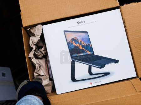 Photo for Bremen, Germany - Dec 10, 2023: A male hand wearing a glove carefully unboxes the Twelve South laptop stand, embodying the concept of unboxing and unpacking - Royalty Free Image