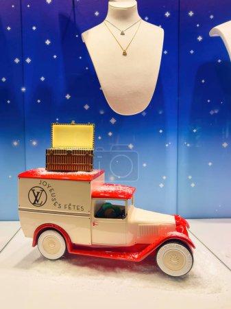 Foto de Estrasburgo, Francia - 25 de diciembre de 2023: Un coche de época, cubierto de nieve, lleva un mensaje de Felices Fiestas en el escaparate de la tienda Louis Vuitton, con elegantes collares y joyas que adornan la - Imagen libre de derechos