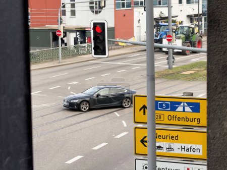 Foto de Kehl, Alemania - 9 de enero de 2024: Un Audi se ve conduciendo frente a tractores que han cerrado carreteras en la ciudad de Kehl, Alemania, como parte de una protesta contra las políticas agrícolas más ecológicas. - Imagen libre de derechos