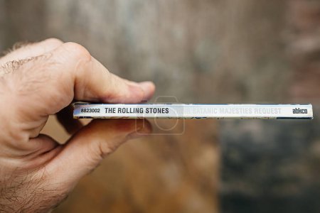 Photo for Paris, France - Jan 12, 2024: A male hand delicately holds the unique and vintage SACD of the iconic album Their Satanic Majesties Request against a natural stone background, showcasing its historical - Royalty Free Image