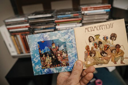 Photo for Paris, France - Jan 12, 2024: A male hand delicately holds the latest The Rolling Stones - Their Satanic Majesties Request SACD alongside the Metamorphosis album in Super Audio CD format, showcasing - Royalty Free Image