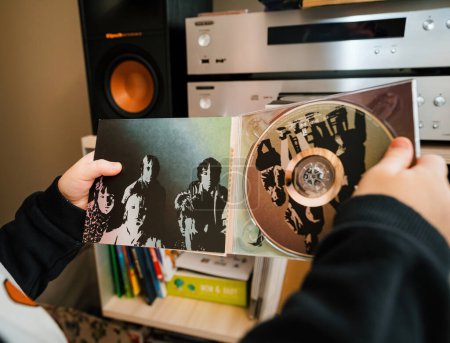 Photo for Paris, France - Jan 17, 2024: A young child holds the SACD version of Aftermath by The Rolling Stones, peering into its booklet - Royalty Free Image