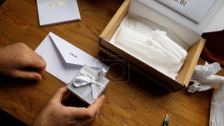 Photo for Paris, France - Jun 5th, 2020: a male hand delicately unboxes a Christian Dior jewelry box, accompanied by a white envelope, unveiling the exquisite luxury of haute couture jewelry. - Royalty Free Image