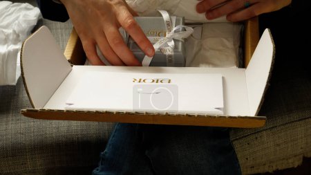 Photo for Paris, France - Jun 5th, 2020: woman unboxing a Christian Dior package, revealing luxurious jewelry inside along with a special secret message from an admirer, creating a moment of excitement and - Royalty Free Image