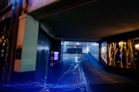 Téléchargez les photos : Les flux de données aux tons bleus sortent d'un parking souterrain, ce qui représente le flux d'informations provenant de sources cachées. - en image libre de droit