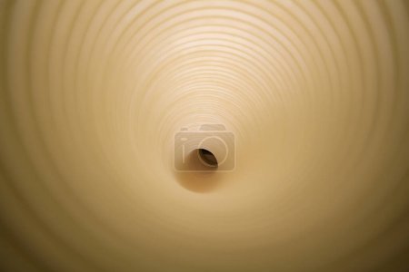 Téléchargez les photos : Vue directe dans un tunnel en plastique beige en papier créant un motif concentrique hypnotique. - en image libre de droit