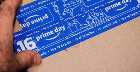 Foto de París, Francia - Jul 4, 2019: Un hombre sostiene con entusiasmo el paquete de cartón de Amazon, con el logotipo de Prime Day, prometiendo un evento de compras especial - Imagen libre de derechos