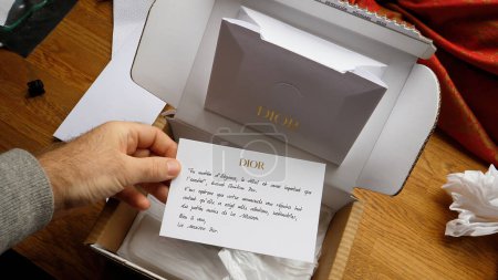 Foto de París, Francia - 14-sep-2023: Una persona desempaqueta un producto Dior con una nota de agradecimiento, mostrando elegancia y marca de alta gama. - Imagen libre de derechos