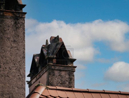 Foto de Chimeneas de piedra adornan la azotea de una casa en Haguenau, Francia, Alsacia, añadiendo al encantador paisaje arquitectónico de la región. - Imagen libre de derechos
