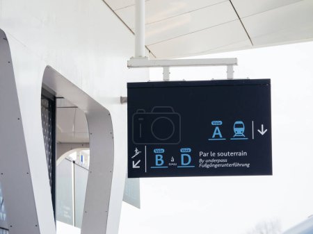 Foto de Un cartel en la estación de tren de Haguenau indica la dirección del paso subterráneo para las vías con instrucciones multilingües para la comodidad del viajero. - Imagen libre de derechos