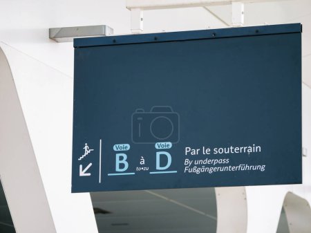 Hinweisschild an einem Bahnhof, das über die Unterführung zu den Bahnsteigen B und D führt, mit mehrsprachigen Anweisungen zur Barrierefreiheit