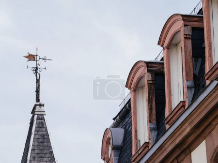 A tall building with a pointed steeple reaching towards the sky, topped with a weather vane spinning in the wind.