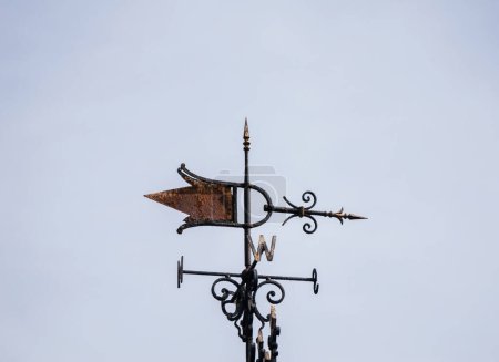A weather vane perched atop a building, spinning with the wind to indicate its direction.