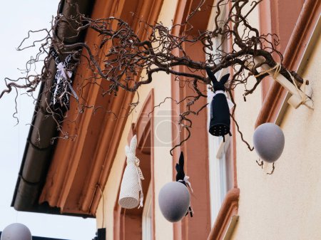 Charming Easter ornaments, including rabbits and eggs, suspended from a tree branch, add festive flair to a street in Haguenau, France