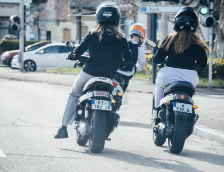 Foto de Haguenau, Francia - 20 de marzo de 2024: Dos mujeres disfrutan de un paseo en ciclomotores rápidos en la ciudad - Imagen libre de derechos