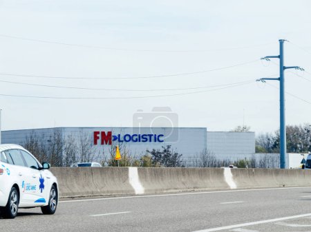 Téléchargez les photos : Haguenau, France - 20 Mar 2024 : Façade d'entrepôt FM Logistics vue de l'autoroute en France, soulignant la présence de l'entreprise dans le secteur de la logistique - en image libre de droit