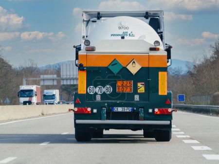 Foto de Estrasburgo, Francia - 20 de marzo de 2024: Un camión grande pintado de verde y naranja conduce por una carretera, rodeado de tráfico y entorno urbano. - Imagen libre de derechos