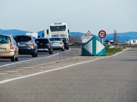 Foto de Estrasburgo, Francia - 20 de marzo de 2024: Una señal de límite de velocidad de 70 kmh adorna la carretera francesa, en medio de una amplia gama de automóviles de varias marcas, con un autobús escolar que navega por la carretera de forma segura - Imagen libre de derechos