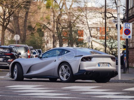 Téléchargez les photos : Strasbourg, France - 20 mars 2024 : Une Ferrari sportive élégante conduisant sur le bord d'une route, réfléchissant la lumière du soleil, sans personne autour. - en image libre de droit