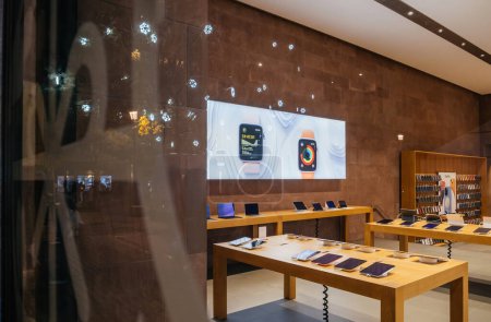 Foto de Estrasburgo, Francia - 23 de diciembre de 2023: Una tienda de Apple vacía por la noche, que muestra un diseño moderno y limpio con los últimos dispositivos tecnológicos que se muestran cuidadosamente en las mesas de madera - Imagen libre de derechos