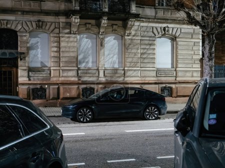 Foto de Estrasburgo, Francia - 23 de diciembre de 2023: Un SUV Tesla eléctrico aparca a lo largo de una calle de Estrasburgo, combinando la innovadora tecnología automotriz con el ambiente histórico de la ciudad. - Imagen libre de derechos