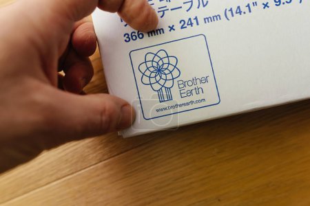 Photo for Paris, France - Mar 9, 2024: Close-up with a male hand pointing to the Brother Earth logo on the sewing table box, featuring multi-language description - Royalty Free Image