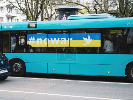 Téléchargez les photos : Francfort, Allemagne - 31 mars 2024 : Un bus urbain bleu vif à Francfort affiche une annonce avec un hashtag et une colombe blanche, symbolisant la paix ou un mouvement social en Ukraine - en image libre de droit