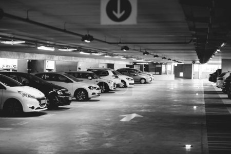 Téléchargez les photos : Un parking souterrain offre un espace sécurisé pour les voitures, à l'abri des intempéries et du vol potentiel dans des tons monochromes - en image libre de droit