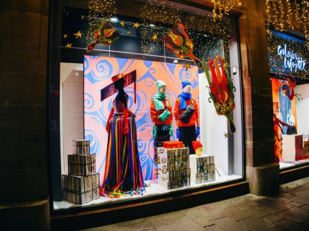 Foto de Estrasburgo, Francia - 23 de diciembre de 2023: Galerías Lafayettes ventana adornada para Navidad, con una variedad de vestidos, títeres y maniquíes - Imagen libre de derechos
