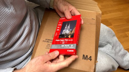 Photo for Frankfurt, Germany - Mar 31, 2024: Person unboxing Canon photo paper, revealing a glimpse of the glossy sheets inside. - Royalty Free Image