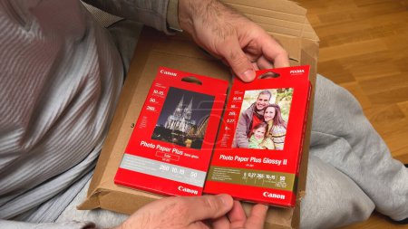 Téléchargez les photos : Francfort, Allemagne - 31 mars 2024 : Deux types de papier photo Canon sont déballés, l'un avec une image de famille et l'autre avec une cathédrale. - en image libre de droit