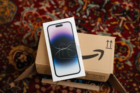 Photo for London, United Kingdom - Sep 29, 2022: Unboxing the latest Apple iPhone 14 Pro from an Amazon cardboard box, featuring the smiling arrow logo, set against a rug in a living room. - Royalty Free Image