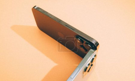 Foto de Londres, Reino Unido - 29-sep-2022: Dos smartphones de la línea de titanio profesional Apple están dispuestos estéticamente sobre un fondo vibrante y colorido - Imagen libre de derechos
