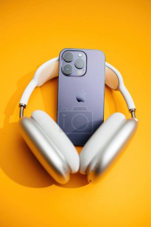 Photo for Paris, France- Sep 29, 2022: An iPhone Pro with luxury Earpods Max headphones set against a vibrant orange background - Royalty Free Image