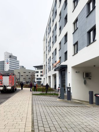 Foto de Freiburg im Breisgau, Alemania - 7 de marzo de 2024: Vista lateral del Aparthotel Adagio Access Freiburg, con el KommTurm SV prominentemente en el fondo y camión de bomberos en frente - Imagen libre de derechos