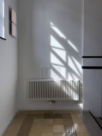 Foto de Un radiador hermoso dentro de un apartamento grande, iluminado por los rayos del sol de la izquierda, calentando el espacio con eficacia. - Imagen libre de derechos