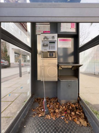 Téléchargez les photos : Kehl, Allemagne - 9 mars 2024 : Une cabine Deutsche Telekom, ses appareils magenta à pièces, montre les fenêtres et les feuilles cassées à l'intérieur, combiné hors du crochet - en image libre de droit