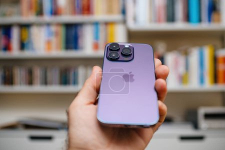 Téléchargez les photos : Londres, Royaume-Uni - 29 sept. 2022 : Une main masculine tient le nouveau corps en acier inoxydable de luxe de qualité titane de l'Apple iPhone 14 Pro dans une couleur violette luxueuse, avec le logo Apple visible - en image libre de droit