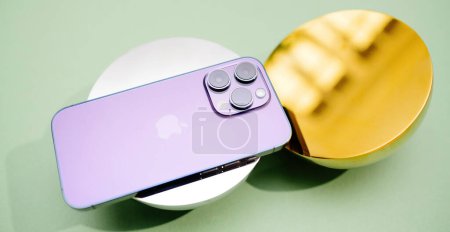 Téléchargez les photos : Londres, Royaume-Uni - 29 sept. 2022 : Un iPhone 14 Pro violet est affiché sur un ensemble d'objets modernes, un or et un argent, soulignant son design élégant et sa finition luxueuse dans un style contemporain - en image libre de droit