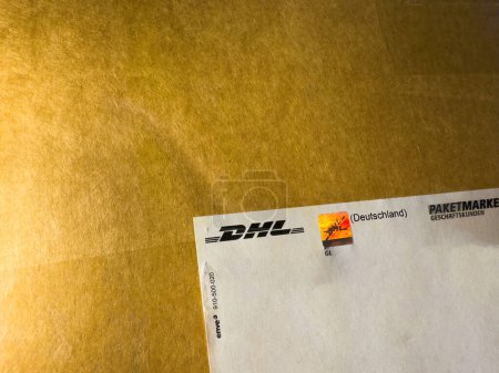 Photo for Frankfurt, Germany - Feb 7, 2024: A close-up macro shot of a reflective sticker featuring the DHL logotype and a rainbow sticker on a delivered parcel, showcasing the vibrant colors and detailed - Royalty Free Image