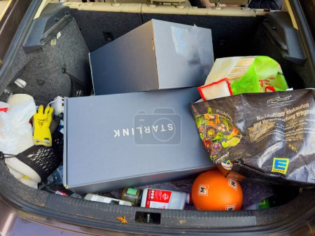 Foto de Berlín, Alemania - Mar 4, 2024: El maletero de un automóvil está lleno de varios artículos, incluyendo dos nuevas cajas Starlink, bolsas de comestibles, artículos de limpieza y una pelota de fútbol. La escena sugiere un día ocupado de - Imagen libre de derechos