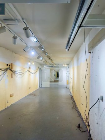 A large store is undergoing reconstruction with wires hanging on the walls and spotlights being turned on, showcasing the renovation and modern updates in progress
