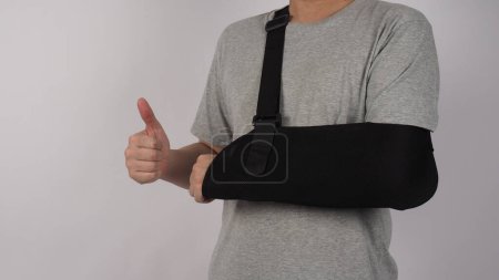 Photo for Broken arm. Arm Sling therapy support and covered around elbow first knuckle broken arm. Post Operative Care. Fractures of humerus radius ulna scapula. Arm Sling after accident. Isolated background. - Royalty Free Image