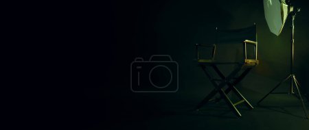 Chaise de réalisateur avec panneau lumineux de cinéma Texte de réalisateur dessus et mégaphone clapet et studio arrière-plan noir. Siège de réalisateur sur un plateau de production vidéo ou de tournage utilisé dans l'industrie cinématographique. Réel pas 3D
