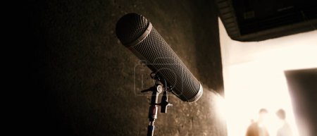 Boom Mikrofon im Set. Boom Mikrofon auf Stativ in der Videoproduktion, das Audio des Talentmodells und Umgebungsgeräusche im Studio aufnimmt. Pro-Mikrofon für Audio-Capture in der Filmindustrie und Audio-Aufnahme.