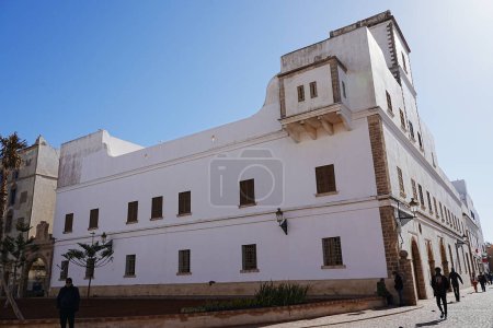 Foto de ESSAOUIRA, MARRUECOS en febrero 2023: Antiguo edificio de esquina blanca en la ciudad africana, cielo azul claro en frío y soleado día de invierno. - Imagen libre de derechos