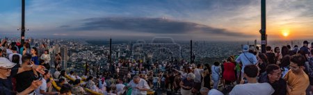 Foto de Bangkok, Tailandia - 20 de febrero. 2024: Los turistas disfrutan de una vista panorámica de Bangkok durante la puesta de sol en la azotea del edificio King Power Mahanakhon, a una altura de 314 metros sobre el suelo. - Imagen libre de derechos