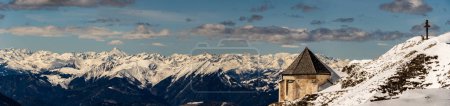 Winter view over the Alps and the epak from Mount Dobratsch, including the Windish Chapel and Mount Grossglockner at the horizon.